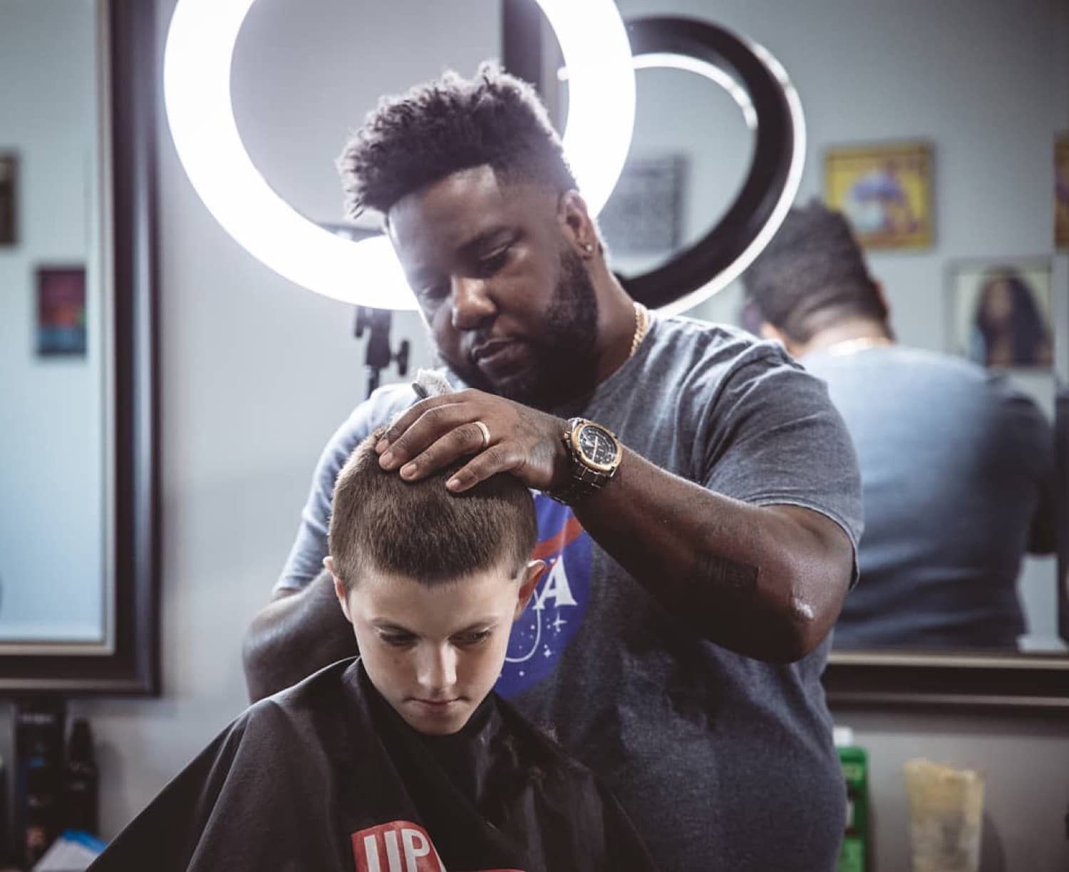 V the Barber lining up a fresh cut under the ring light.